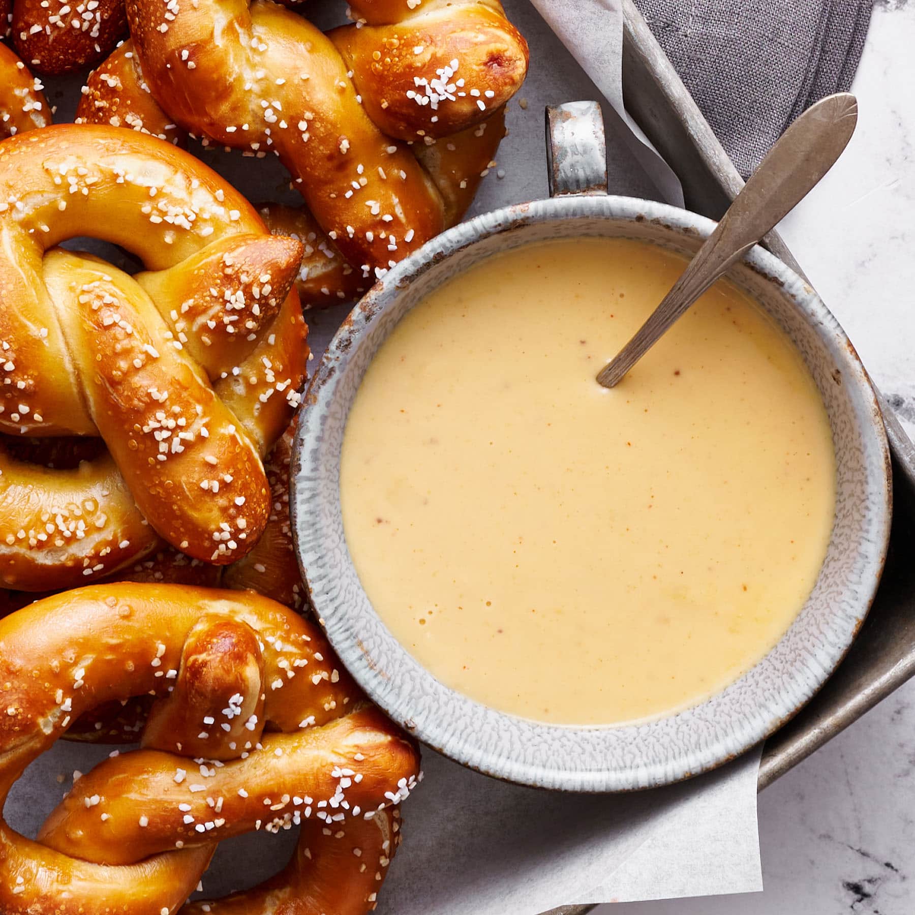 easy homemade beer cheese sauce in a bowl with homemade pretzels surrounding it