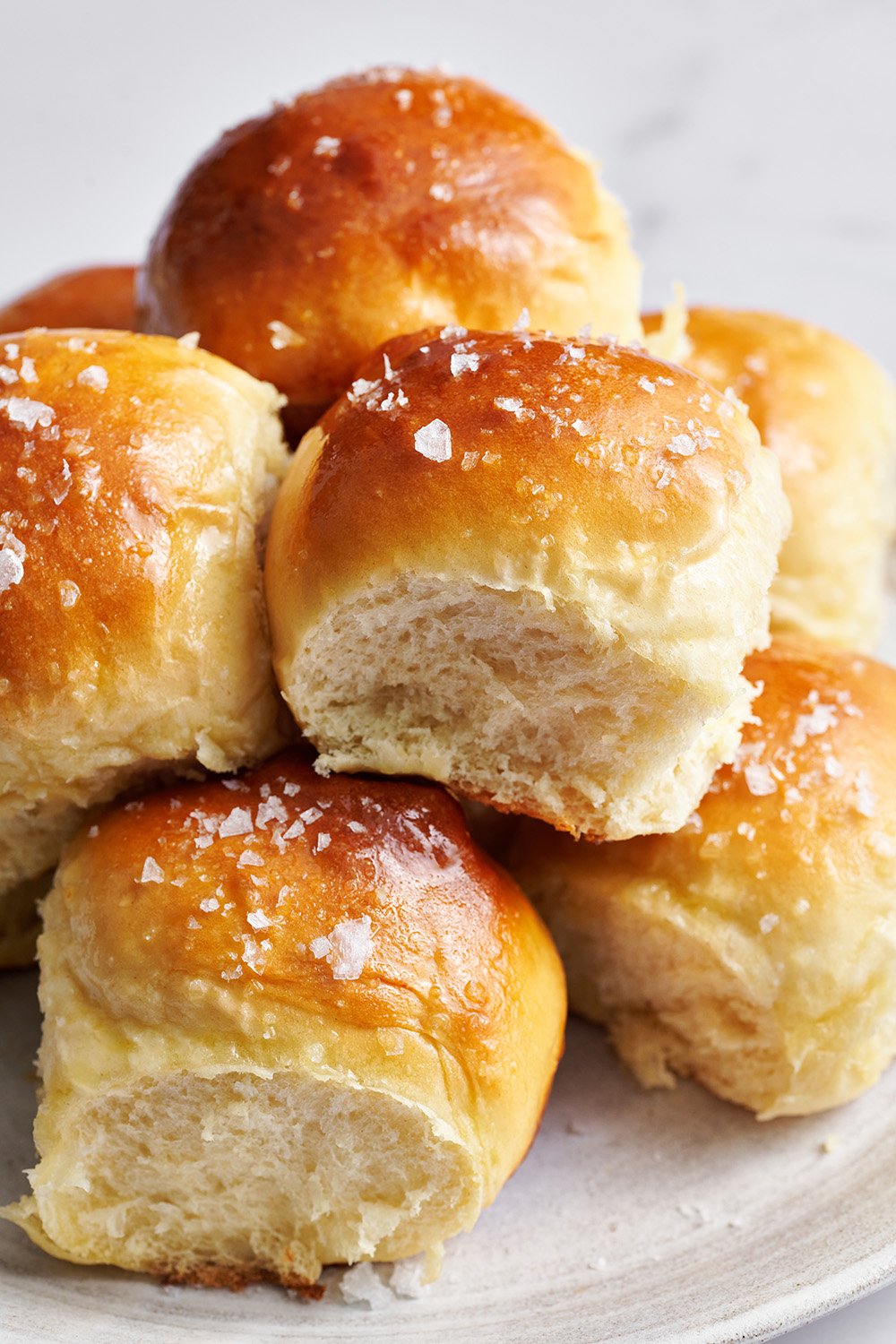 a pretty pile of rolls on a plate, all topped with flaky sea salt. 
