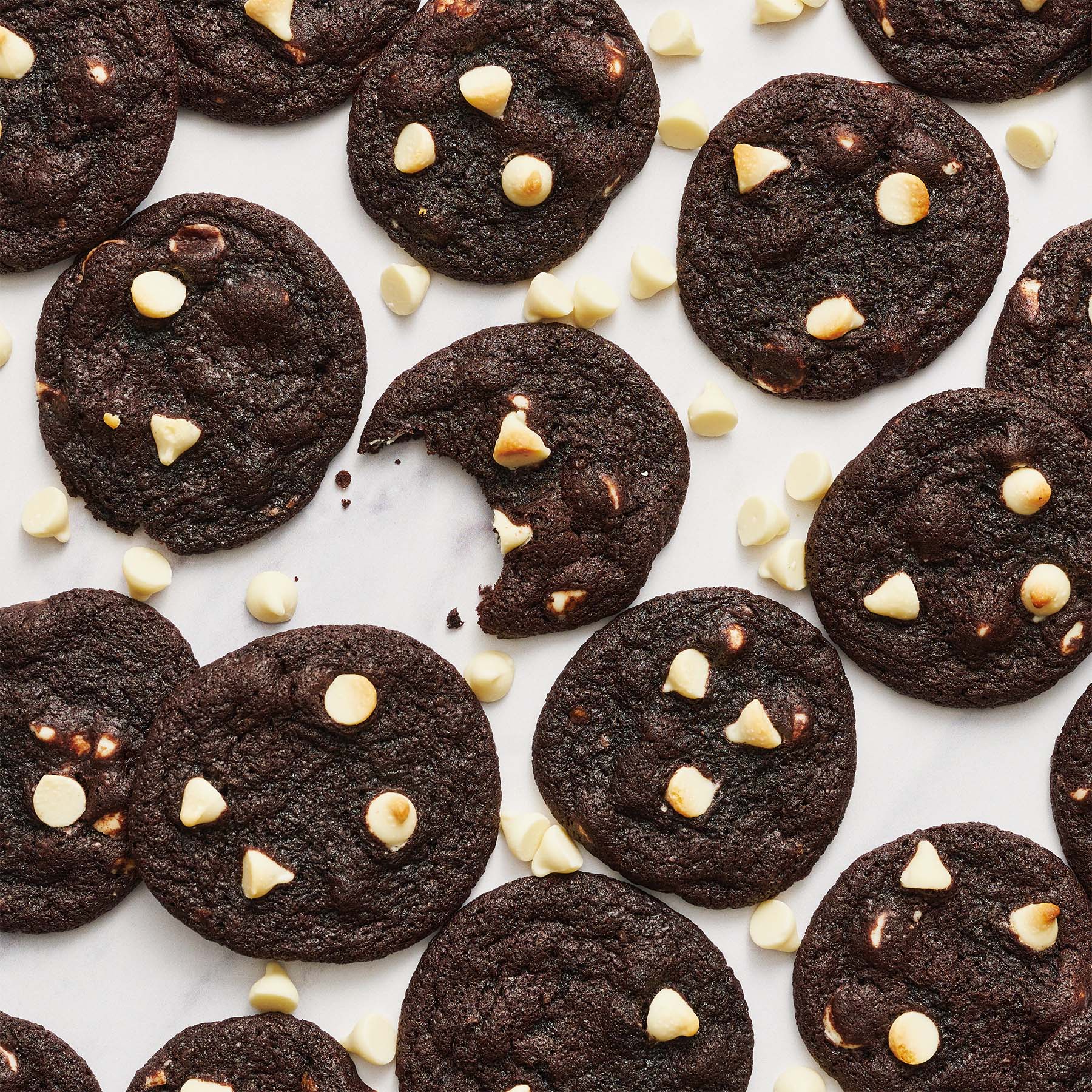 black and white paradise bakery copycat cookies on parchment paper with white chocolate chips scattered