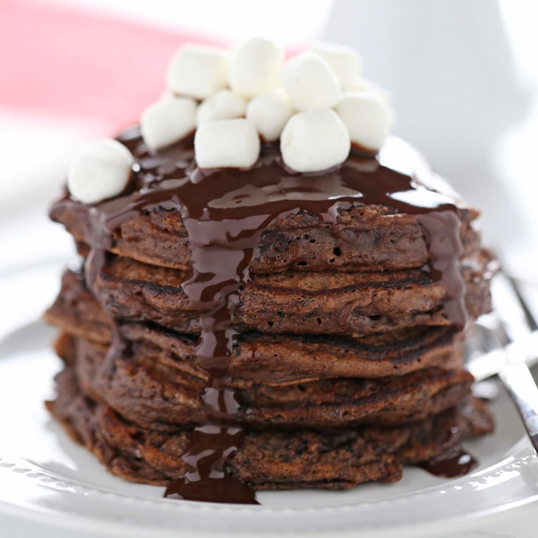 Hot Chocolate Pancakes feature rich chocolate buttermilk pancakes with a thick chocolate fudge topping and garnish with mini marshmallows.