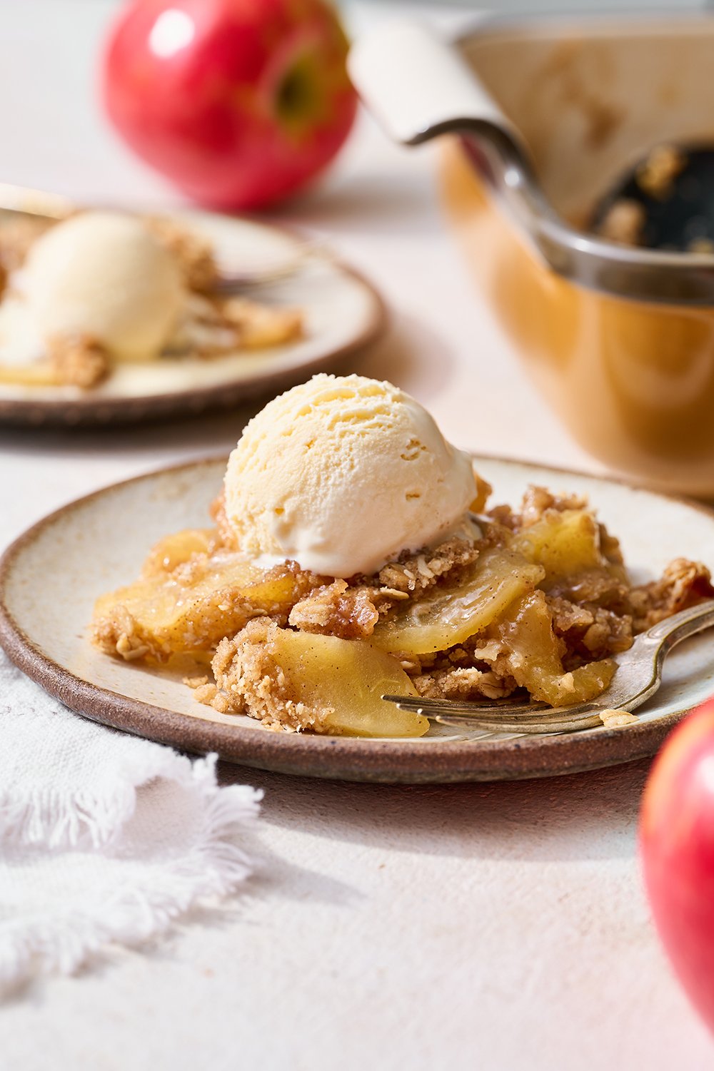 a serving of apple crisp on a plate with a scoop of vanilla ice cream on top