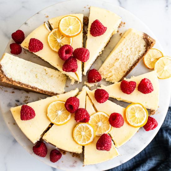 slices of cheesecake with fresh raspberries and some lemon slices for decoration