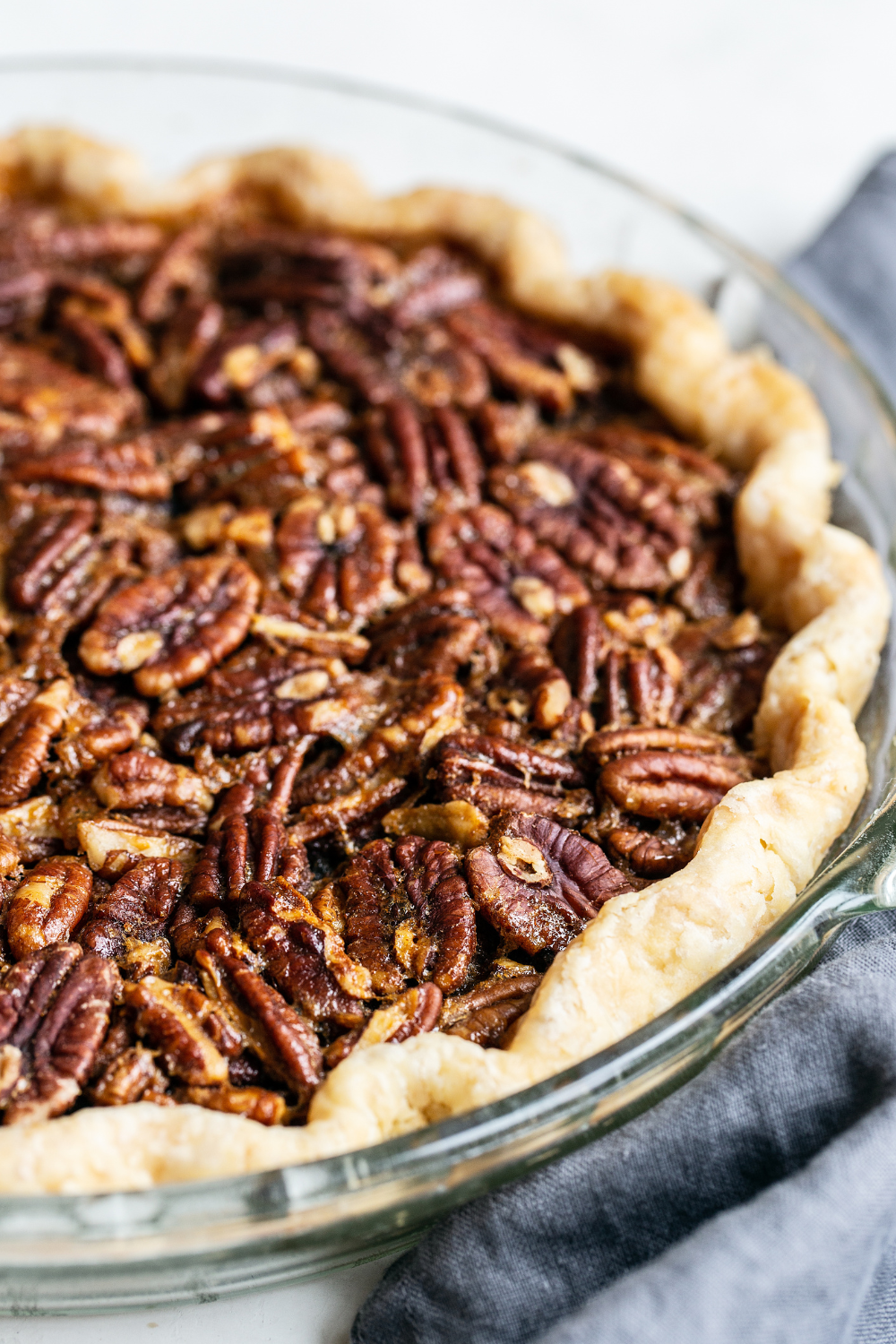 a whole, unsliced pecan pie in a glass pie pan.