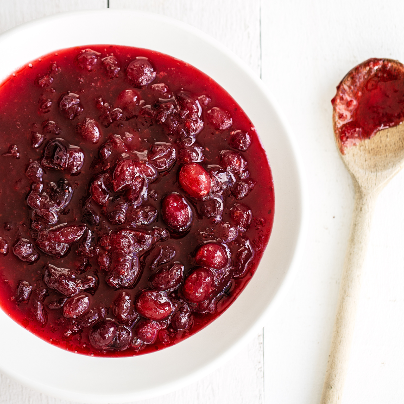a bowl of cranberry sauce with a spoon next to it to serve.