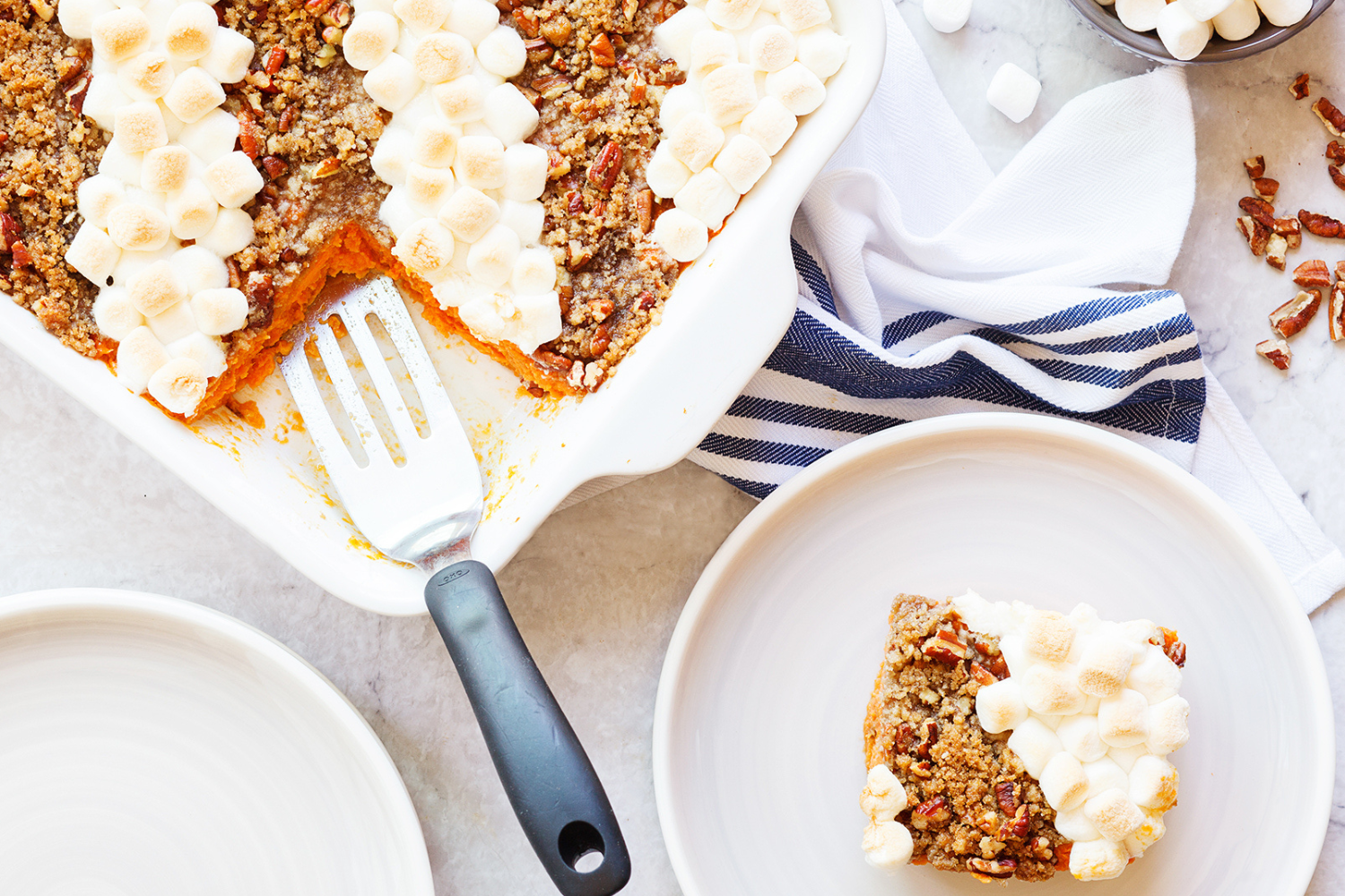 the Crowd-Pleasing Sweet Potato Casserole in a white ceramic baking dish, being served onto plates.