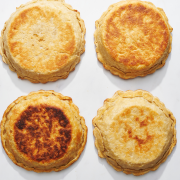 four pie crusts baked in different types of pie pans