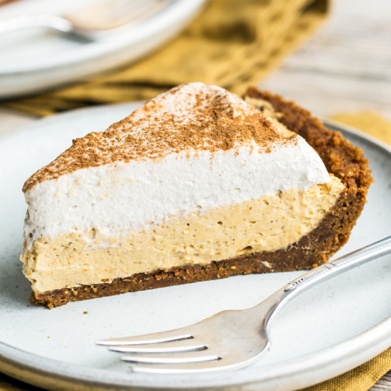 a perfect slice of pumpkin mousse pie on a white plate beside a fork, ready to enjoy.