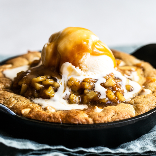 apple pie pizookie with salted caramel sauce and vanilla ice cream on top, to serve