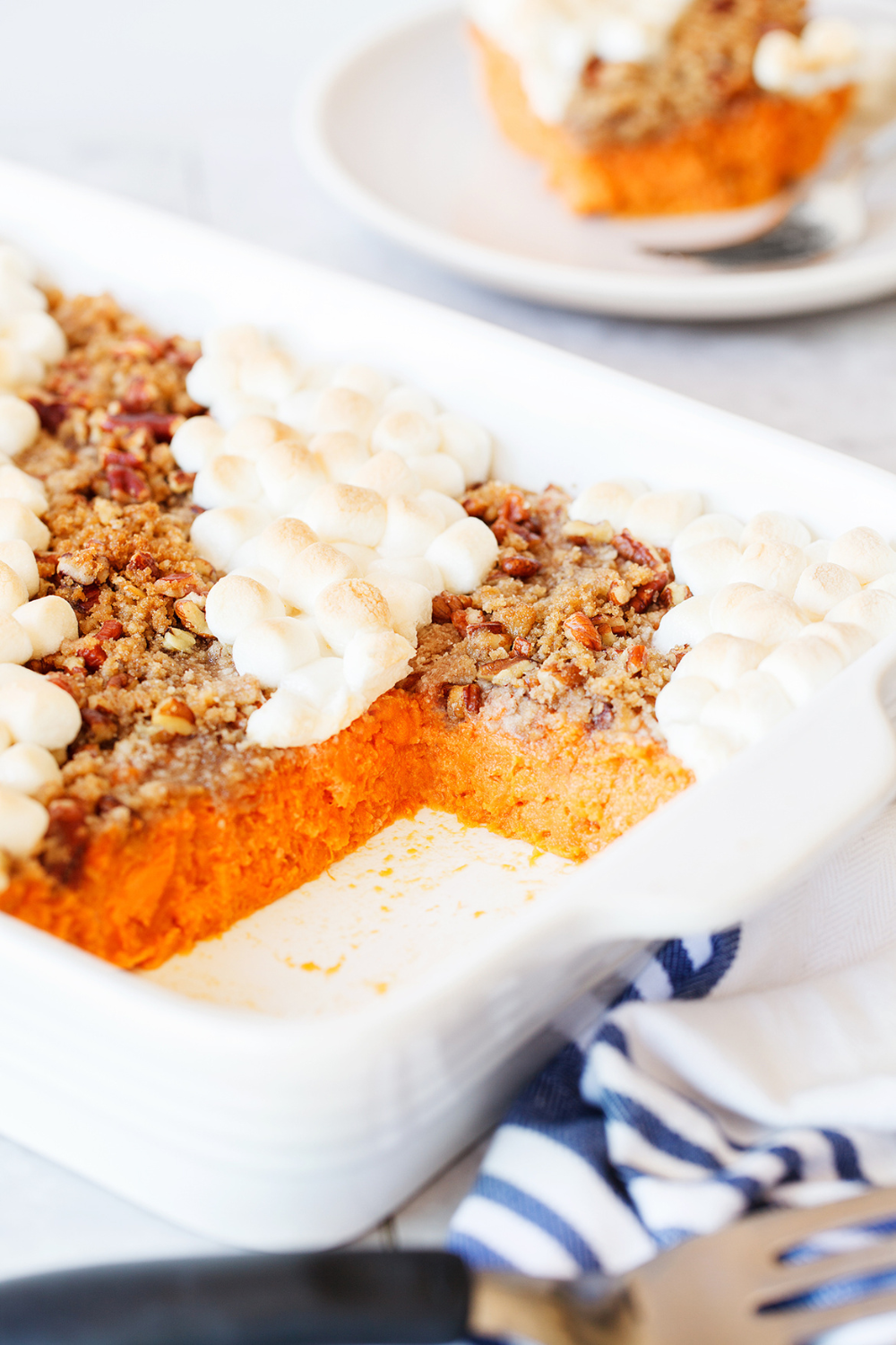 this Crowd-Pleasing Sweet Potato Casserole with a slice removed, showing the pretty, vibrant orange sweet potatoes inside.